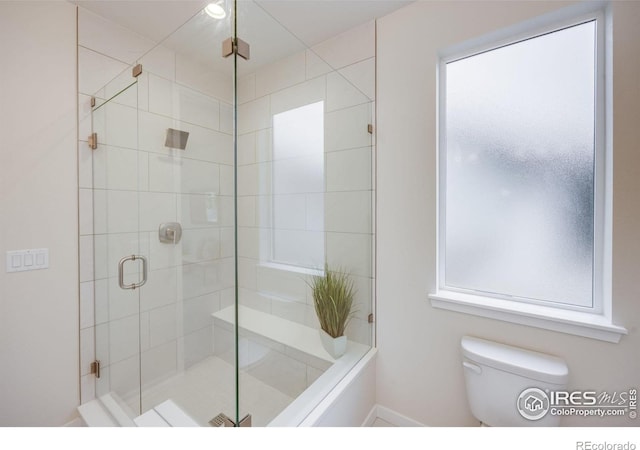 bathroom with a wealth of natural light, toilet, and an enclosed shower