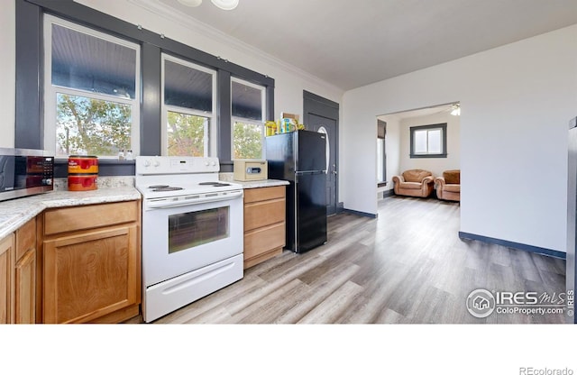 kitchen with ornamental molding, light hardwood / wood-style floors, black fridge, and white range with electric cooktop