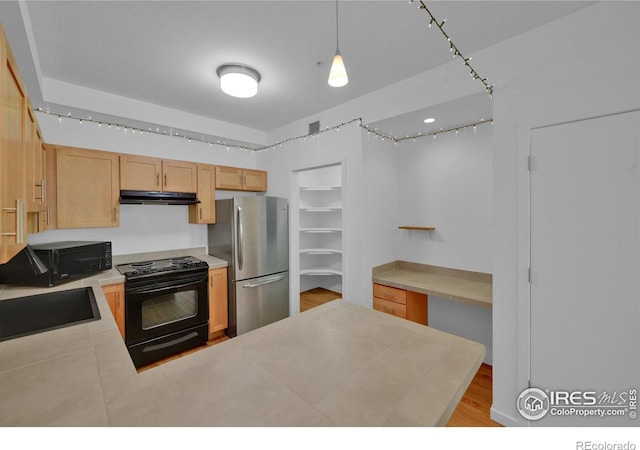 kitchen with hanging light fixtures, black appliances, sink, light brown cabinets, and light hardwood / wood-style flooring