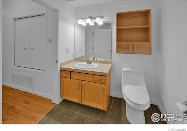 bathroom with toilet, vanity, and tile patterned flooring