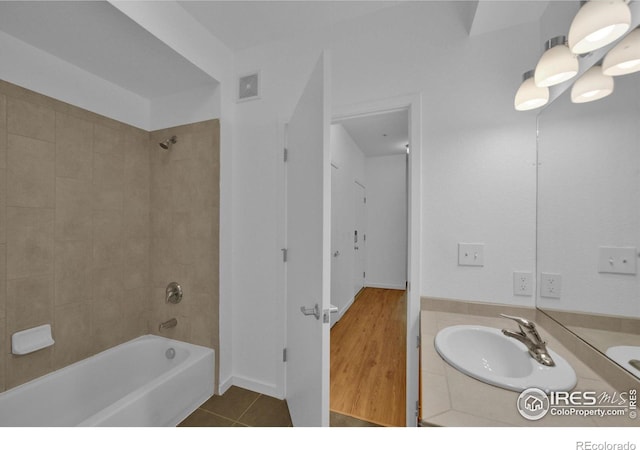 bathroom with hardwood / wood-style flooring, vanity, and tiled shower / bath combo