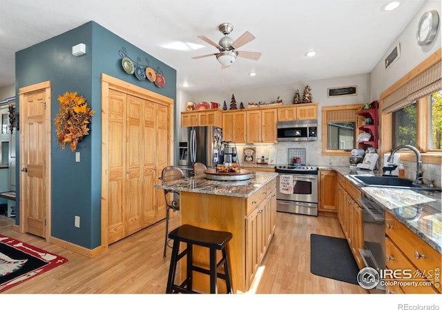 kitchen featuring stainless steel appliances, sink, a kitchen breakfast bar, a kitchen island, and light wood-type flooring