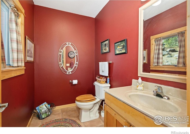 bathroom with toilet, vanity, and tile patterned floors