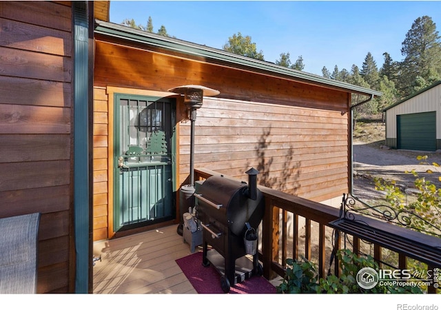 deck with a garage, grilling area, and an outbuilding