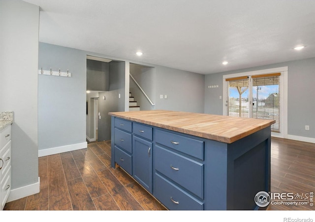 kitchen with blue cabinets, a kitchen island, wood counters, and dark wood-style floors