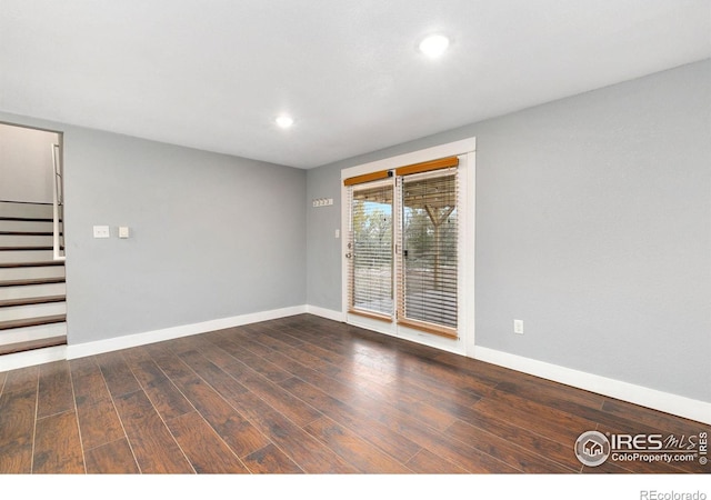 unfurnished room with recessed lighting, dark wood finished floors, baseboards, and stairs