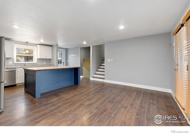 kitchen with white cabinets, a kitchen island, dark wood-type flooring, light countertops, and stainless steel dishwasher