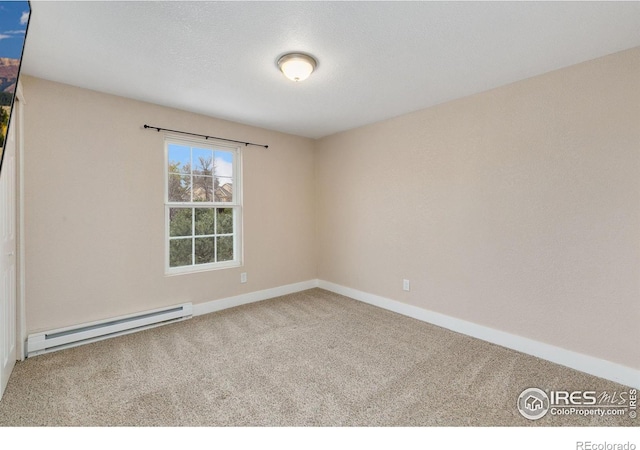 spare room featuring a baseboard heating unit, carpet flooring, and baseboards