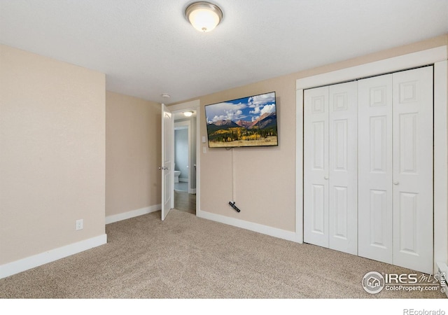 unfurnished bedroom with a textured ceiling, carpet floors, a closet, and baseboards