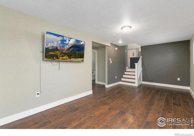 spare room featuring dark wood-style floors, stairs, and baseboards