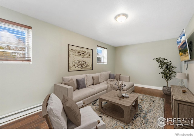 living area featuring a baseboard heating unit, dark wood-style flooring, and baseboards