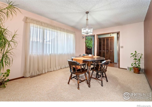 dining room with a textured ceiling, an inviting chandelier, and carpet floors