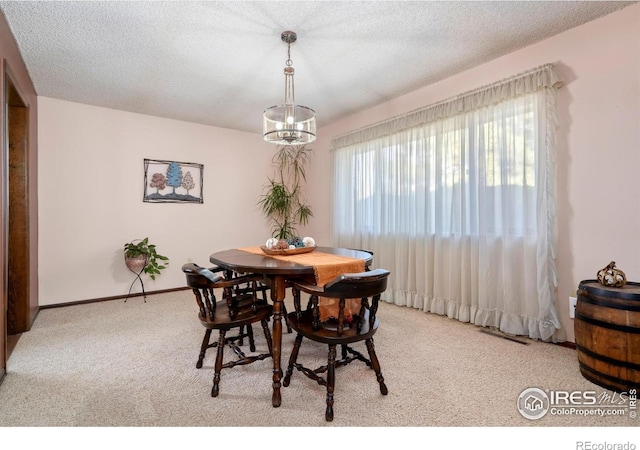 dining area featuring light colored carpet, a textured ceiling, and a chandelier