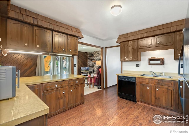 kitchen with dishwasher, wood walls, sink, and dark hardwood / wood-style floors