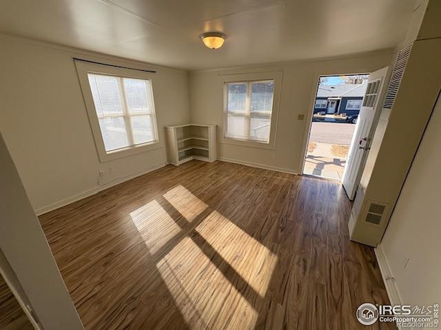 unfurnished room with dark hardwood / wood-style flooring and a healthy amount of sunlight