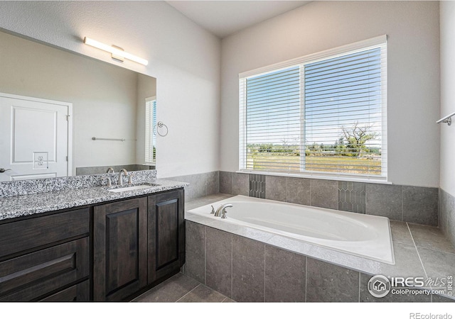 bathroom with tile patterned floors, vanity, and tiled bath