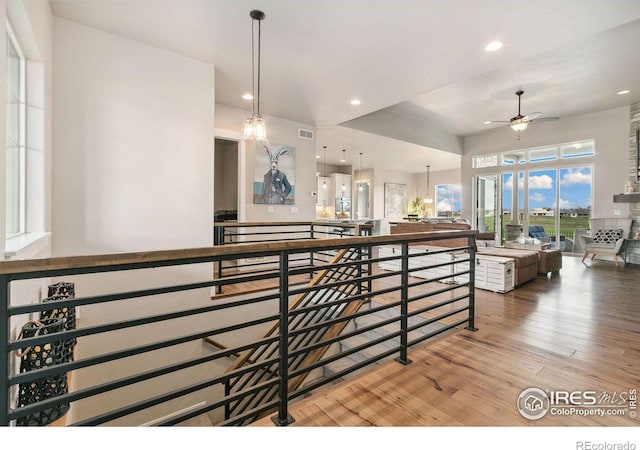 stairs featuring wood-type flooring and ceiling fan with notable chandelier