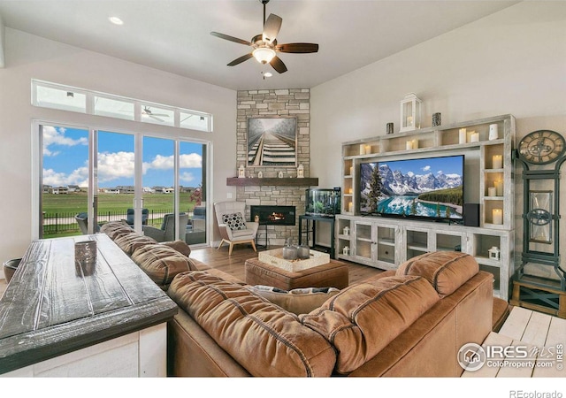 living room with wood-type flooring, ceiling fan, and a fireplace