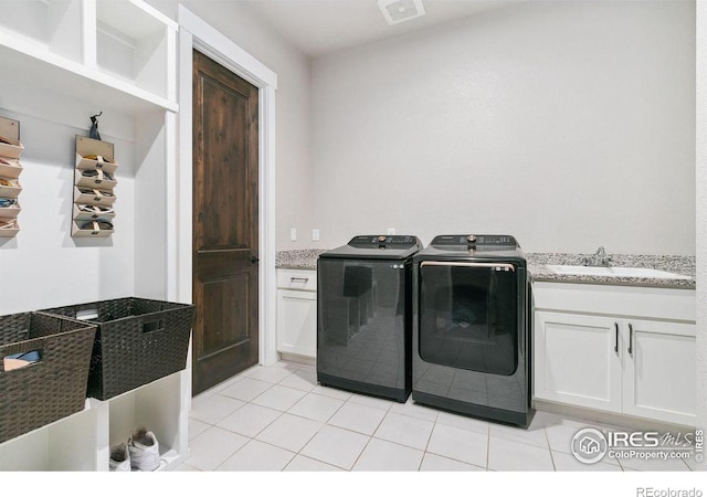 clothes washing area with washing machine and dryer, cabinets, sink, and light tile patterned floors