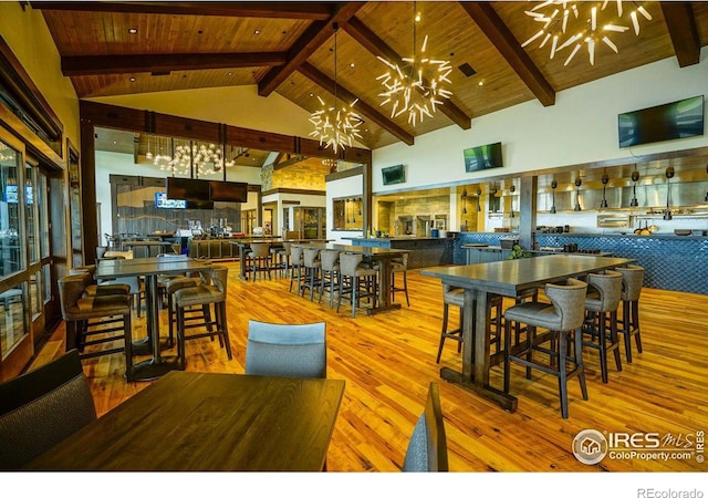 dining space with high vaulted ceiling, light hardwood / wood-style flooring, beamed ceiling, and a chandelier