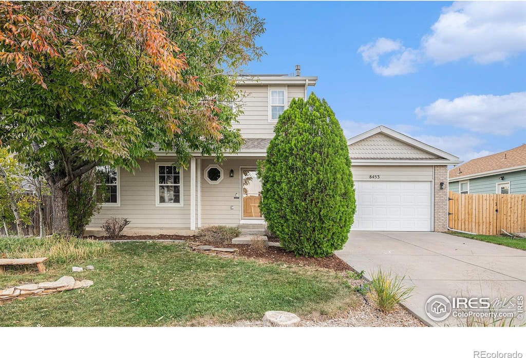 view of property hidden behind natural elements with a garage and a front yard