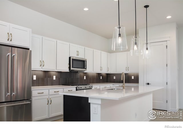 kitchen featuring a center island with sink, stainless steel appliances, white cabinetry, and hanging light fixtures