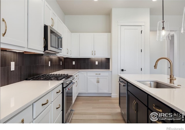 kitchen with stainless steel appliances, sink, tasteful backsplash, white cabinets, and pendant lighting