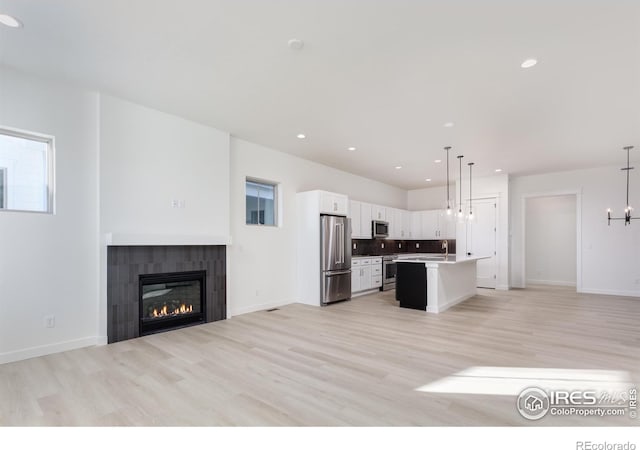 kitchen featuring a center island, appliances with stainless steel finishes, white cabinets, a chandelier, and pendant lighting