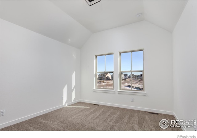 carpeted empty room with vaulted ceiling