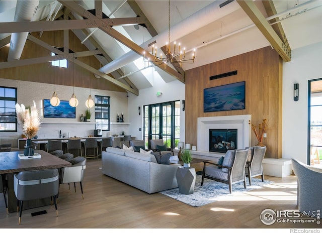 living room with high vaulted ceiling, a chandelier, wood-type flooring, and beamed ceiling