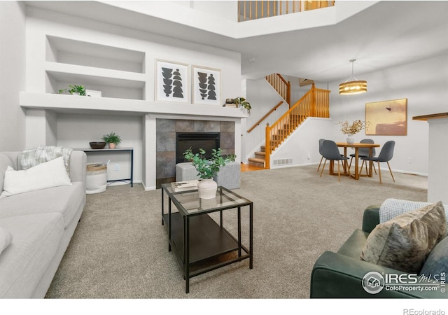 living room with carpet, a tiled fireplace, and a towering ceiling