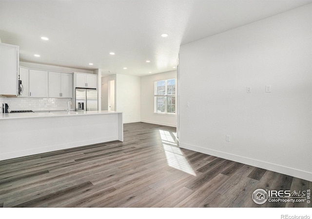 kitchen with stainless steel appliances, white cabinets, backsplash, and dark hardwood / wood-style flooring