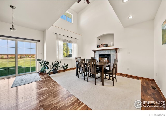 dining room featuring a fireplace, a high ceiling, ceiling fan, and dark hardwood / wood-style flooring