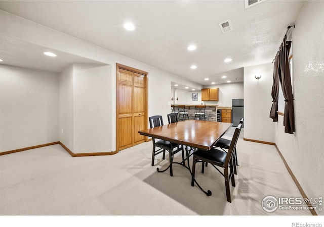 dining space with bar and light colored carpet