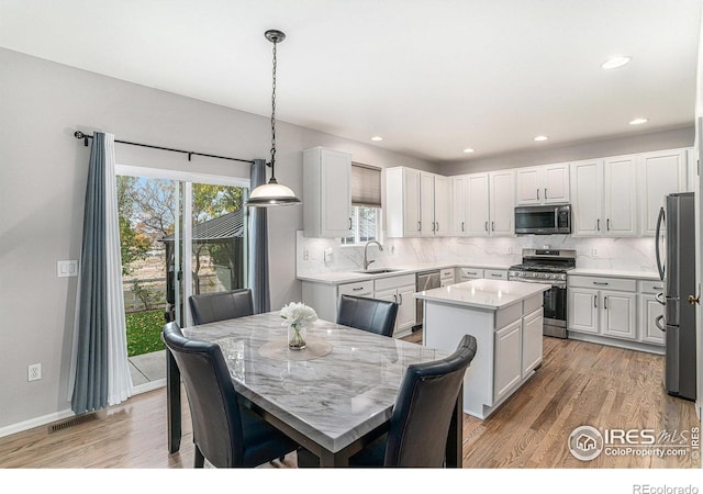 kitchen with white cabinetry, appliances with stainless steel finishes, pendant lighting, sink, and a center island