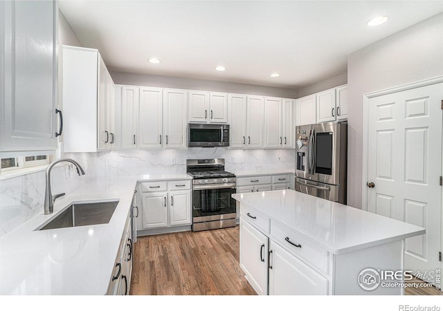 kitchen featuring tasteful backsplash, light wood-type flooring, appliances with stainless steel finishes, sink, and white cabinets