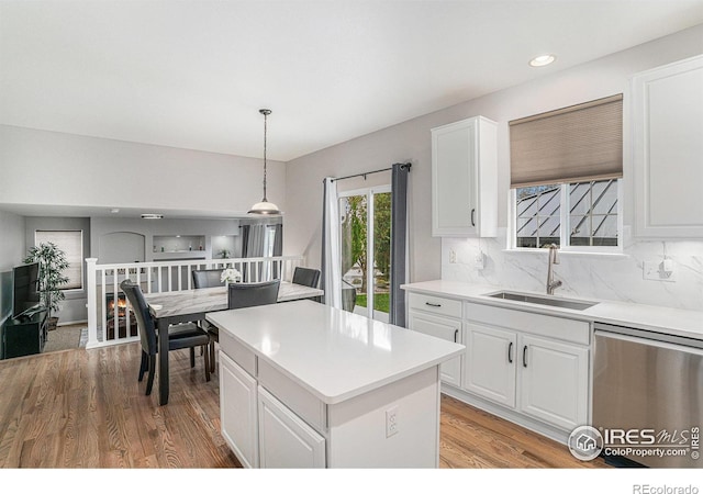 kitchen with dishwasher, light hardwood / wood-style flooring, sink, and pendant lighting