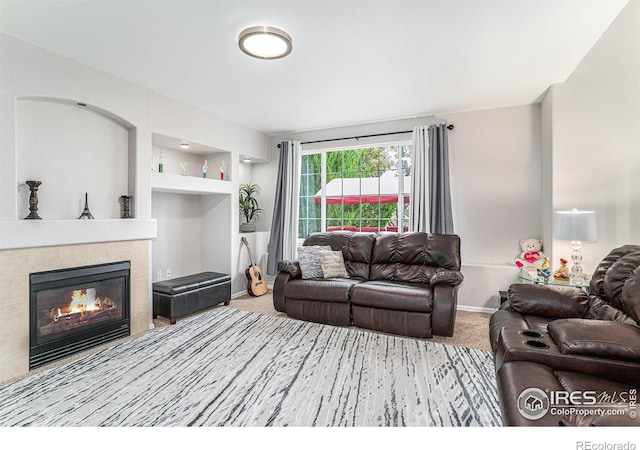 carpeted living room featuring a tiled fireplace and built in features