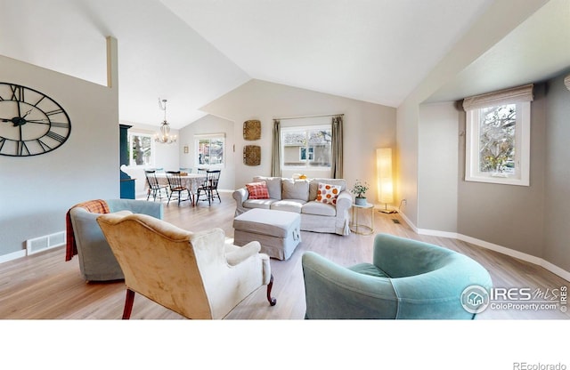 living room featuring a chandelier, light hardwood / wood-style floors, and lofted ceiling