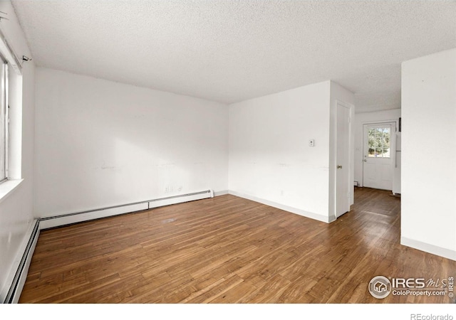 spare room with wood-type flooring, baseboard heating, and a textured ceiling