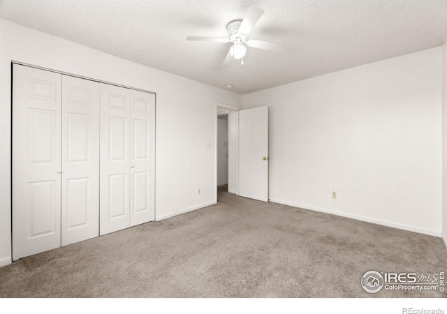 unfurnished bedroom with ceiling fan, a textured ceiling, a closet, and light colored carpet