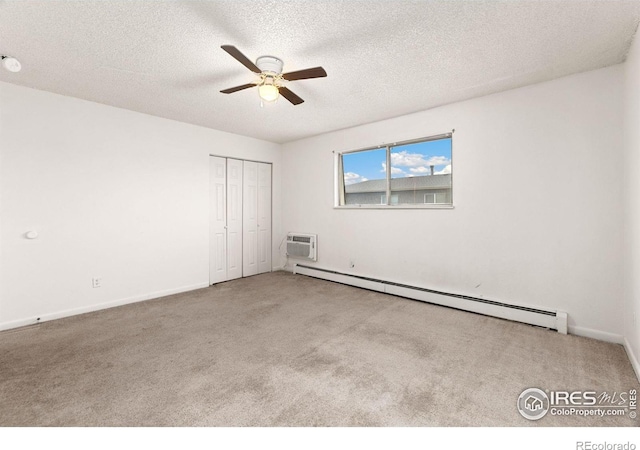 carpeted spare room with a wall mounted AC, a textured ceiling, ceiling fan, and a baseboard radiator