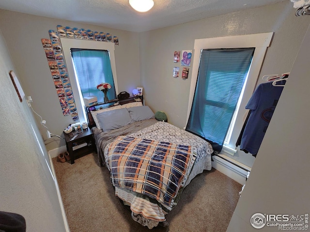 bedroom with a baseboard heating unit, carpet, and a textured ceiling