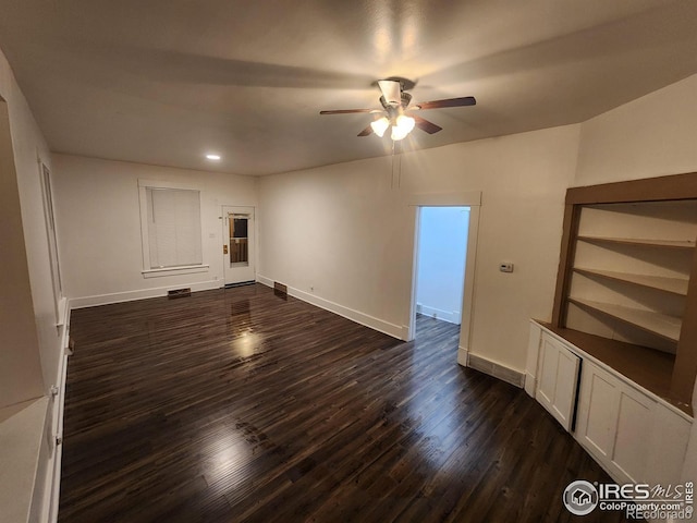 empty room featuring visible vents, dark wood finished floors, baseboards, and ceiling fan