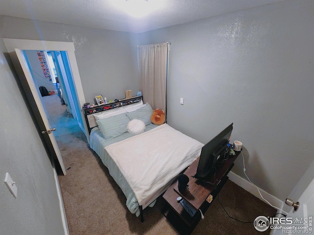 carpeted bedroom featuring a textured ceiling and baseboards