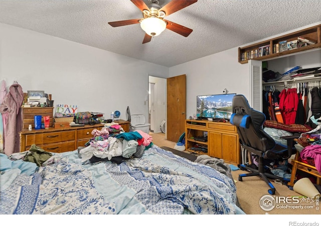 bedroom with a textured ceiling, light colored carpet, ceiling fan, and a closet