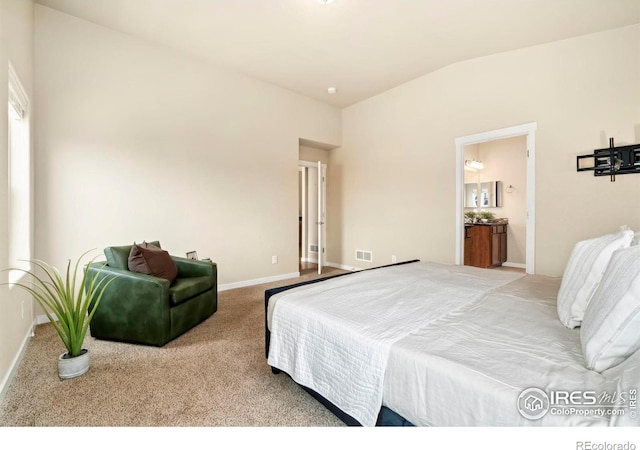 bedroom with ensuite bathroom, light carpet, and vaulted ceiling