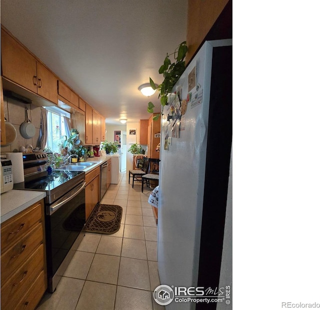 kitchen with stainless steel appliances, light tile patterned floors, and sink