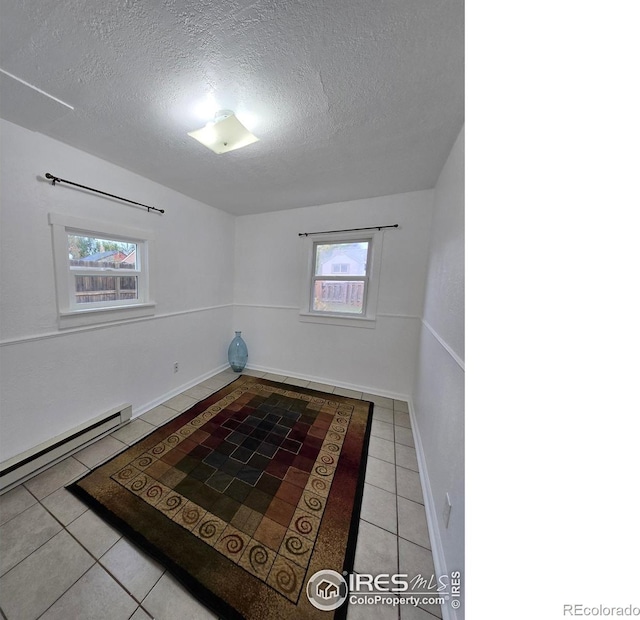 spare room featuring a textured ceiling and light tile patterned floors