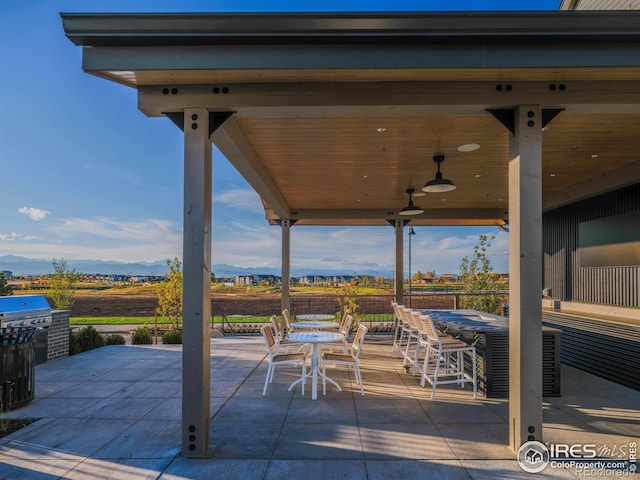 view of patio with an outdoor bar, ceiling fan, and a mountain view